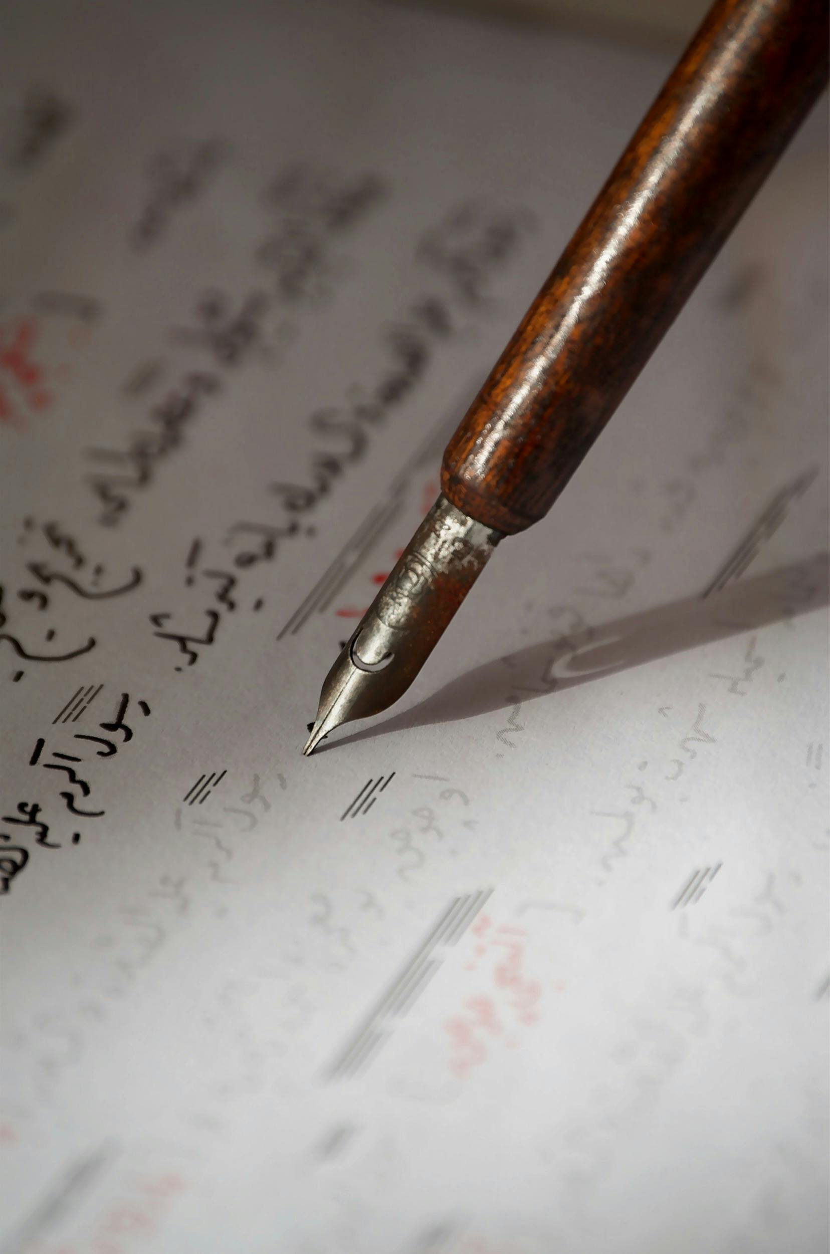 photo-hero-15 An intimate view of a vintage fountain pen poised over handwritten Arabic text.